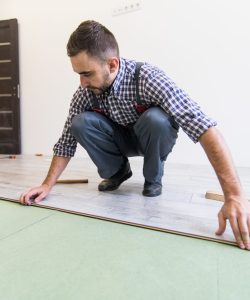 Young worker laying a floor with bright laminated flooring boards